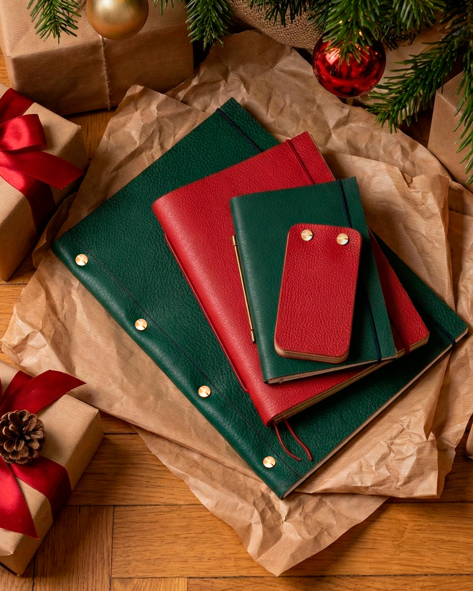 Carnet en cuir Novum Organum cobalt personnalisé et rechargeable de la Compagnie du Kraft posé sur un plaid et entouré de cadeaux de Noël